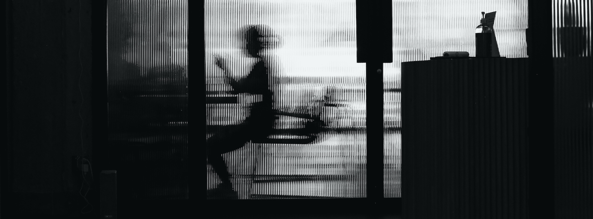 blurry woman sitting working behind door