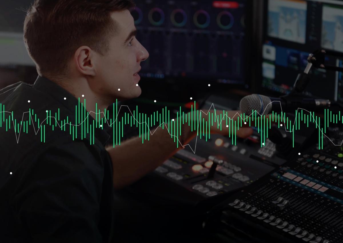 Hombre operando equipos de audio en un estudio de grabación. Habla cerca de un micrófono mientras ajusta los controles de una consola de sonido. En la parte frontal de la imagen, hay una superposición gráfica de ondas sonoras en verde y blanco, representando la captura y análisis del audio